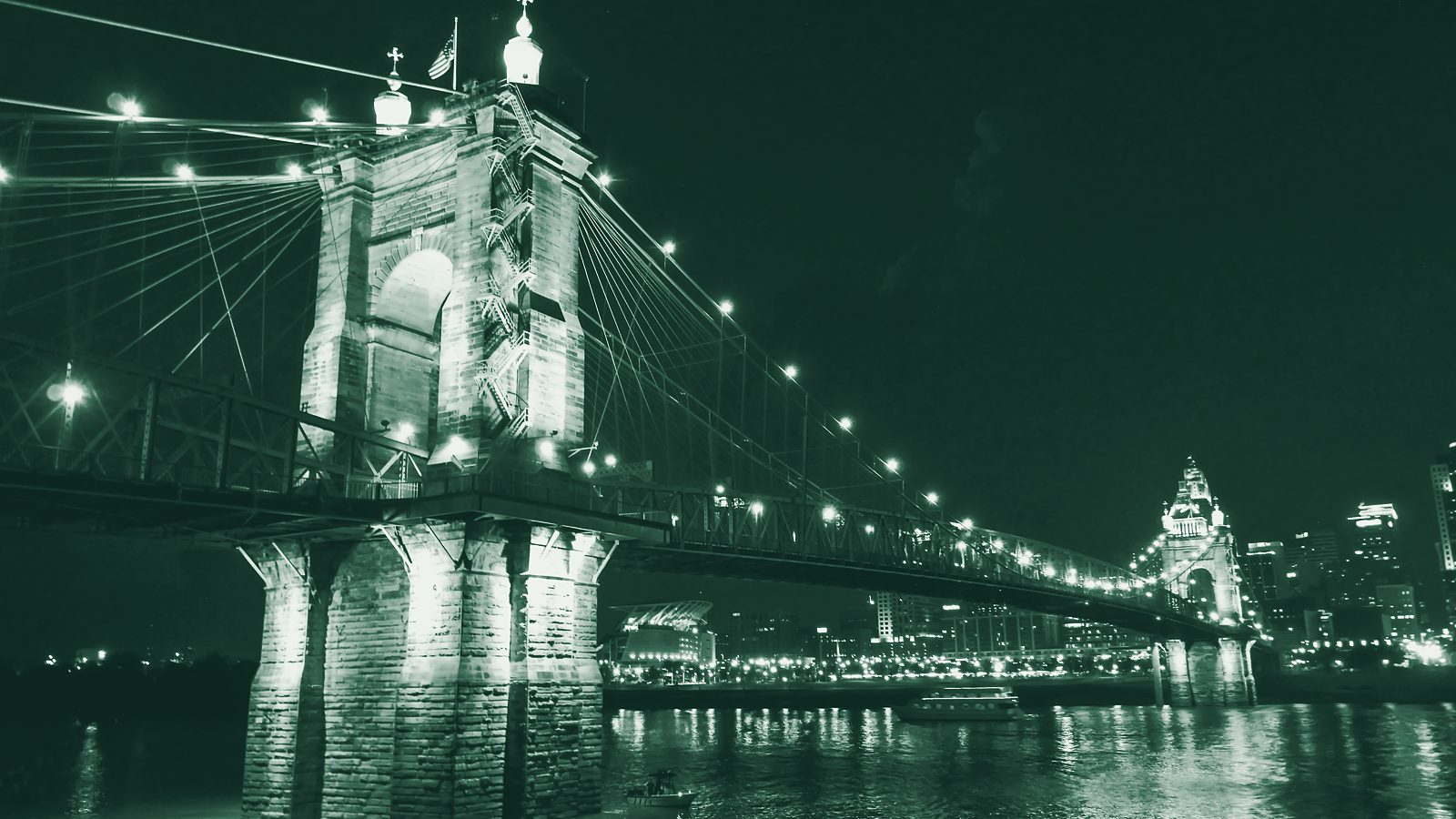 A lit suspension bridge spanning a river at night