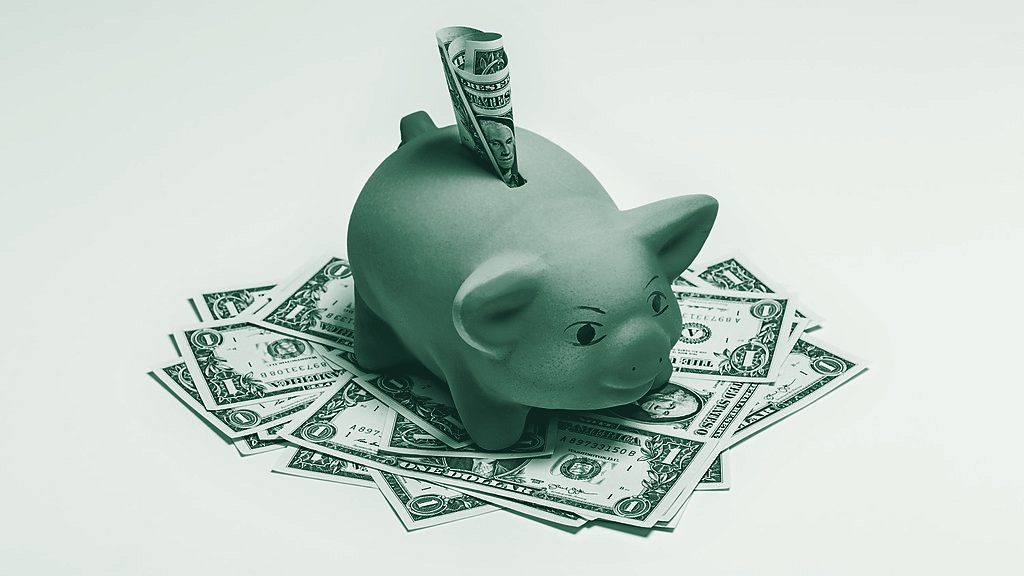 A pink piggy bank standing on scattered US dollar bills